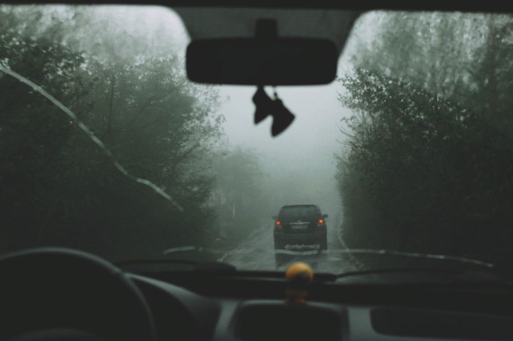 Gloomy car ride in dense fog, capturing mysterious road atmosphere.