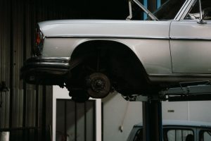 A classic car is elevated on a lift in a professional auto repair garage, showcasing its undercarriage.
